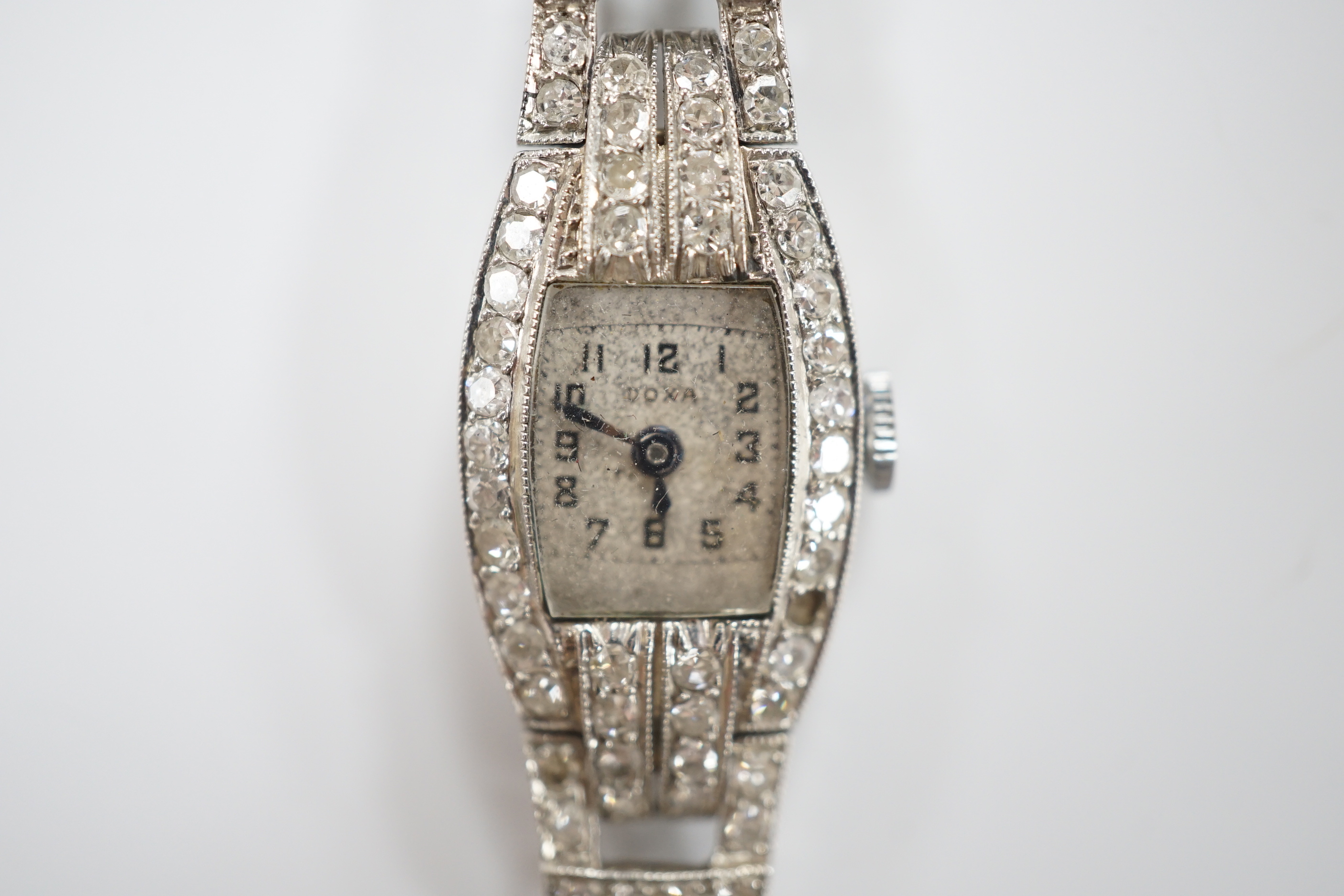 A lady's 1930's/1940's French white metal (platinum mark) and diamond cluster set manual wind cocktail watch, on a twin fabric strap, with metal clasp.